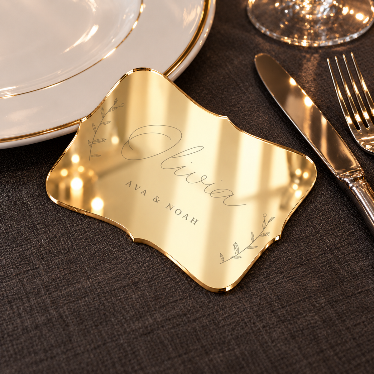 Digital lifestyle visualisation of Olivia mirror gold acrylic place card on a charcoal dining table; styling props not included.