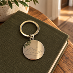 AI visualisation of a silver mirror keyring with a mountain line-art engraving example
