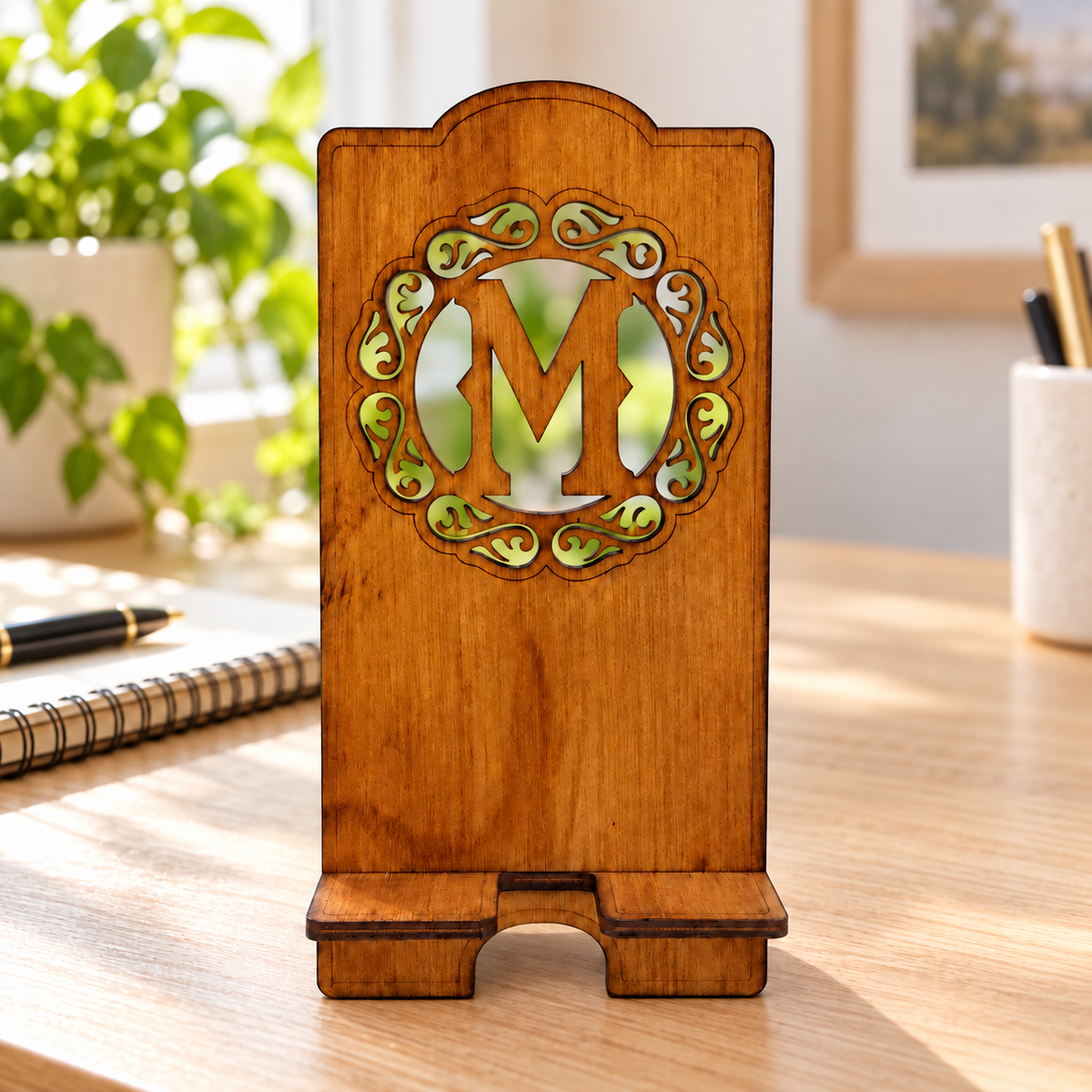Digital lifestyle visualisation of the warm brown wooden phone stand with a custom initial example; desk props not included.