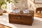 Two twisted whisky glasses and wooden gift box in soft daylight
