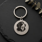 Brushed stainless steel dog keyring on dark slate with eucalyptus leaves